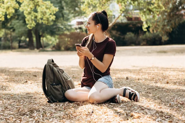 Joven hermosa chica positiva está sentado y escuchando música — Foto de Stock