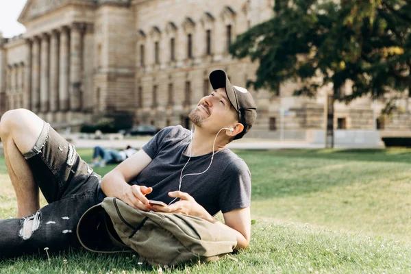 Student, leží na trávě a poslouchá hudbu. — Stock fotografie