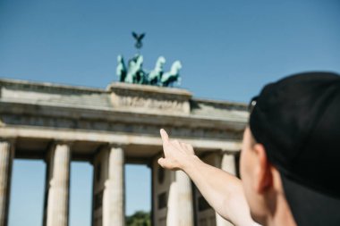Turist veya adam elini Berlin Brandenburg Kapısı üzerinde gösterir