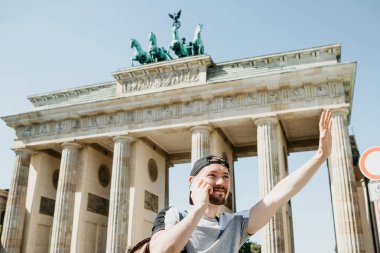 Bir turist ya da bir adam bir sırt çantası ile bir cep telefonu üzerinde konuşurken ve birisi eliyle tebrik.