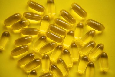 Sarı bir arka plan üzerinde pek çok saydam hapları Omega 3 ya da balık yağı