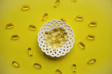 Sarı bir arka plan üzerinde pek çok saydam hapları Omega 3 ya da balık yağı