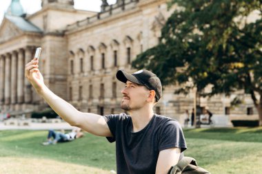 Genç erkek turist veya video bağlantısı üzerinde konuşmak veya telefon kullanarak iletişim kurmak veya fotoğraf öğrenci