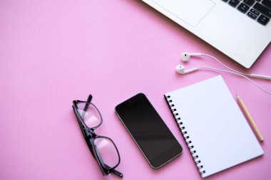 Çalışma alanı'nda bir moda pembe renk. Bir dizüstü bilgisayar da dahil olmak üzere birçok farklı şey, kulaklık, cep telefonu ve dizüstü masaya vardır.