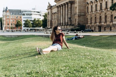 Güzel genç kız Almanya'da Leipzig sokakta çimenlerin üzerinde dinlenme.