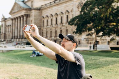 Genç erkek turist veya video bağlantısı üzerinde konuşmak veya telefon kullanarak iletişim kurmak veya fotoğraf öğrenci