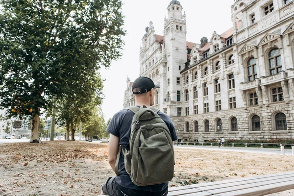 Mladý muž sedí na lavičce na ulici v Lipsku v Německu. — Stock fotografie