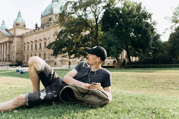 Студент лежит на траве и слушает музыку . — стоковое фото