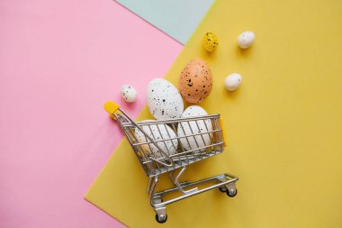 Çok renkli bir arka plan üzerinde yumurta ile alışveriş sepeti.