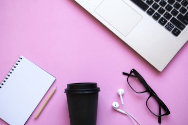 Çalışma alanı'nda bir moda pembe renk. Masanın üzerinde bir laptop ve kulaklık da dahil olmak üzere birçok farklı şeyler vardır