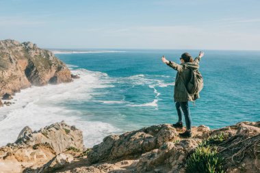 Ne kadar memnun olduğunu Hiking kız ellerini yukarı yükseltir Portekiz Atlas Okyanusu'nda yakınındaki sırt çantası ile gösterir