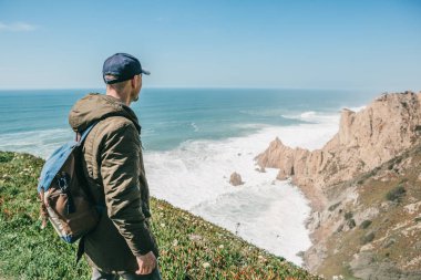 Bir sırt çantası ile bir adam turist yalnızlık Portekiz Cape Roca'da duruyor