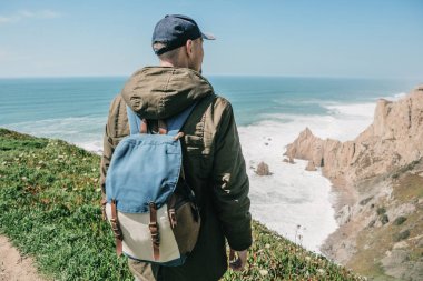 Bir sırt çantası ile bir adam turist yalnızlık Portekiz Cape Roca'da duruyor