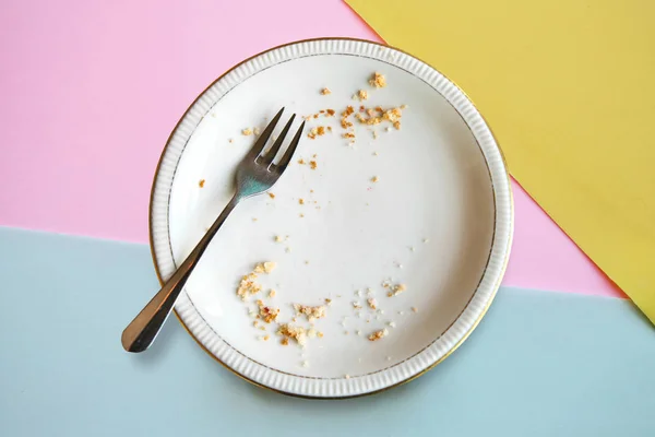 Empty plate with crumbs after eating on a color background. The concept of the end of the holiday or celebration — Stock Photo, Image