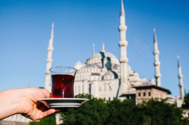 Sultanahmet Camii manzaralı terasında geleneksel Türk çay tutan kadın.