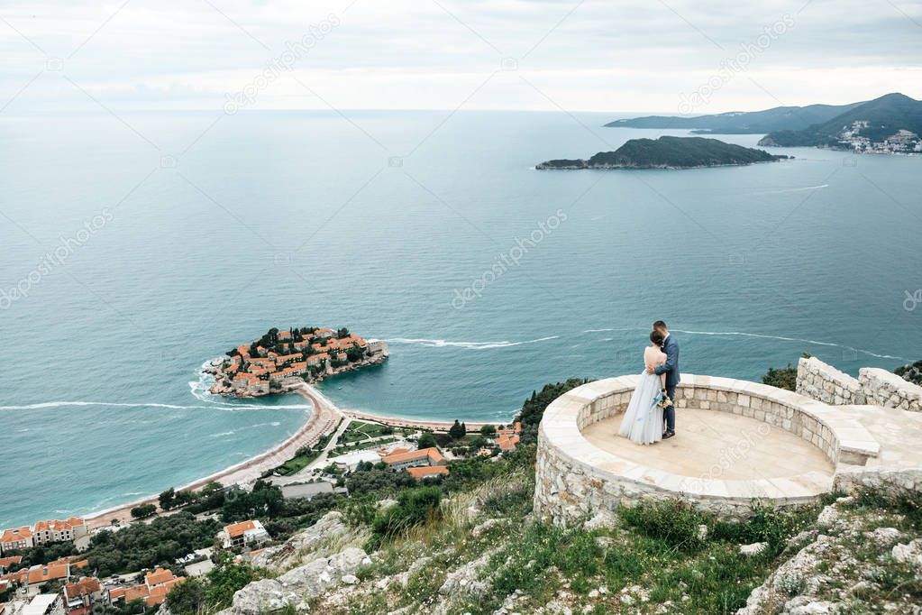 Couple looks at the island of Sveti Stefan in Montenegro