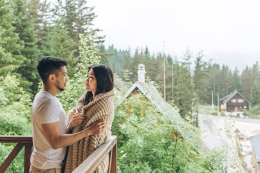 Bir adam balkonda bir kadına sarılır.