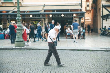 İtalya, Verona, Haziran 01, 2019: Yaşlı bir adam kalabalık bir yerde elleriyle yüzünü kapatır veya öksürür veya hapşırır.