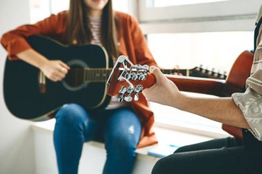 Gitar çalmayı öğreniyorum. Öğretmen öğrenciye gitar çalmanın temel kurallarını açıklar. Bireysel evde eğitim ya da ders dışı eğitim.