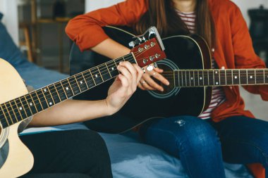 Gitar çalmayı öğreniyorum. Öğretmen öğrenciye gitar çalmanın temel kurallarını açıklar. Bireysel evde eğitim ya da ders dışı eğitim.