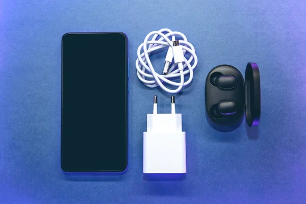핸드폰 헤드폰 파란색 배경의 충전기 — 스톡 사진
