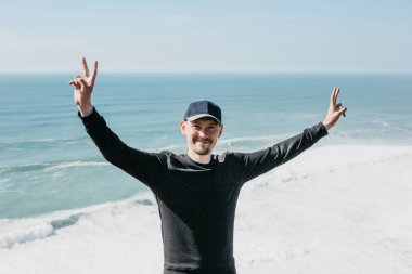 Olumlu bir adam parmaklarını deniz veya okyanus zeminine karşı barış ya da zafer anlamına gelen bir işaret olarak gösterir..