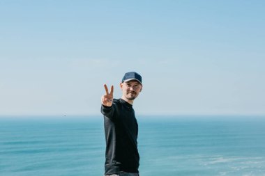 Olumlu bir adam parmaklarını deniz veya okyanus zeminine karşı barış ya da zafer anlamına gelen bir işaret olarak gösterir..