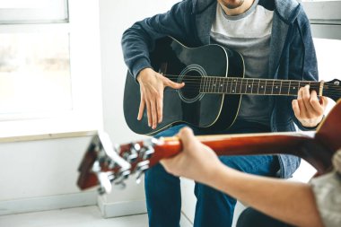 Gitar çalmayı öğreniyorum. Öğretmen öğrenciye gitar çalmanın temel kurallarını açıklar. Bireysel evde eğitim ya da ders dışı eğitim.
