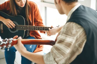 Gitar çalmayı öğreniyorum. Öğretmen öğrenciye gitar çalmanın temel kurallarını açıklar. Bireysel evde eğitim ya da ders dışı eğitim.