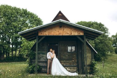 Gelin ve damat evin yanında duruyorlar. Kırsal mı, kırsal mı?