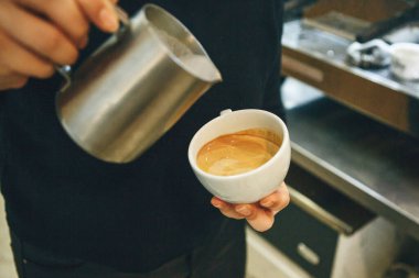 Barista kahveye süt döker.