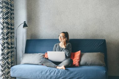 Evden çalışan bir kız ya da bir öğrenci evden ya da serbest çalışan bir öğrencidir. Dizüstü bilgisayar ve telefon kullanıyor..