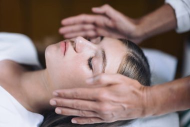 Tutarak Reiki terapisti hasta baş ve transfer enerji her iki tarafta eller. Güzel ve huzurlu genç kız gözleriyle yalan kapalı. Alternatif tedavi kavramı. 