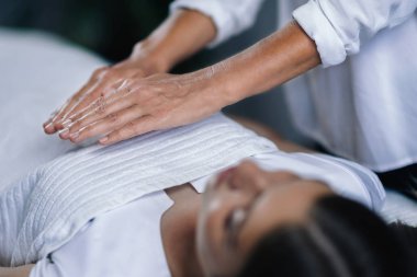 Yatay görüntü tutan kadın Reiki terapisti Kalp Çakra Şifa hasta göğüs üzerinde eller. Huzurlu güzel genç kız kapalı gözleriyle yalan.