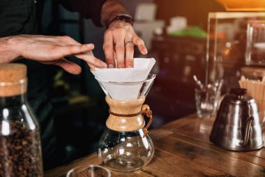 Filtre kahve barista eller görüntü kadar kapatın. Barista dövmeli silah karanlık üniforması ile.   