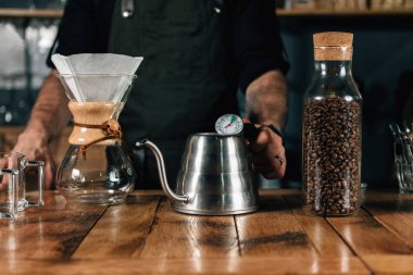 Su ısıtıcısı termometre ile tutarak barista, yakın çekim. Barista ve filtre kahve yapmak için aletler.