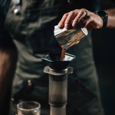 Hava içine dökerek kahve barista kahve makinesi tuşuna basın. Barista dövmeli silah karanlık üniforması ile. 
