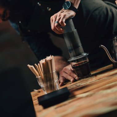 Barista kahve basın hava yapma dikey görüntü kadar kapatın. Barista dövmeli silah karanlık üniforması ile
