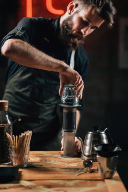 Barista kahve basın hava yapma dikey görüntü kadar kapatın. Barista dövmeli silah karanlık üniforması ile.  