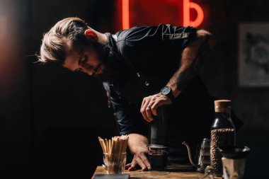 Aeropress kahve barista yatay görüntü kadar kapatın. Barista dövmeli silah karanlık üniforması ile