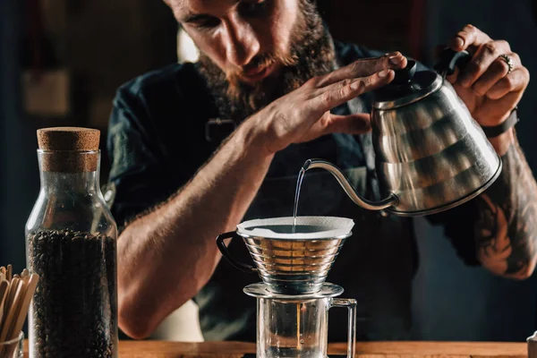 关闭一个年轻的男性咖啡师将开水注入卡利塔波滴水机 在咖啡店的数字规模上煮咖啡和测量它 巴里斯塔穿着深色制服制作桌上滴布咖啡的工具和设备 — 图库照片