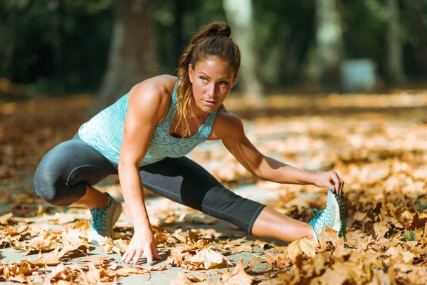 Woman stretching in the park, in the fall.