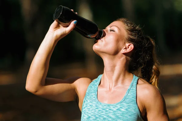 Woman after Exercising Outdoors in The Fall . Resting and drinking water