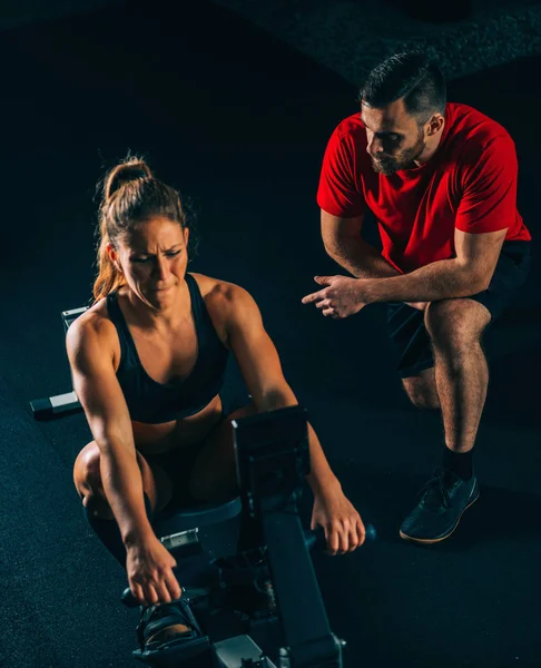 Cross training. male trainer with female athlete exercising on rowing machine