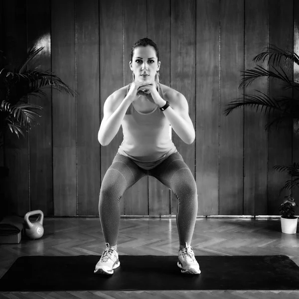 Woman Doing Squats on High-intensity interval training at home.