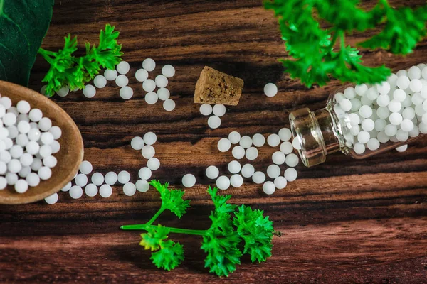 木のスプーンでホメオパシー錠剤 新鮮な葉 木製の背景 ホメオパシーの概念とホメオパシーの球と小さなボトルの完全 — ストック写真