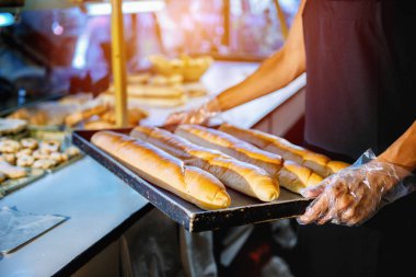 Bayan baker ile taze pişmiş baget Pişirme tepsisi tutan eller. 