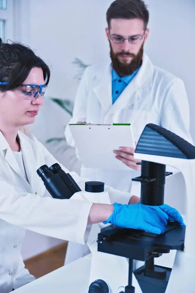 Jonge Vrouw Wetenschapper Doen Testlaboratorium Met Microscoop Mannelijke Wetenschapper Notities — Stockfoto