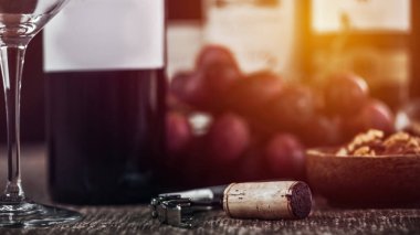 Tirbuşon şişe açacağı, boş şarap cam, ahşap kase fındık ve arka planda taze üzüm ile kompozisyon.