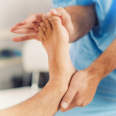 Fizyoterapist iyileştirici tedavi hasta ayak yapıyor. Terapist mavi üniforma giydiği bildirildi. Osteopati, Chiropractic ayak ayarlama